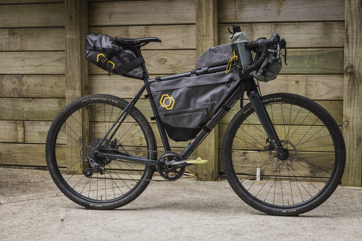 Kona Rove DL with Apidura Frame Bags in front of a wooden wall